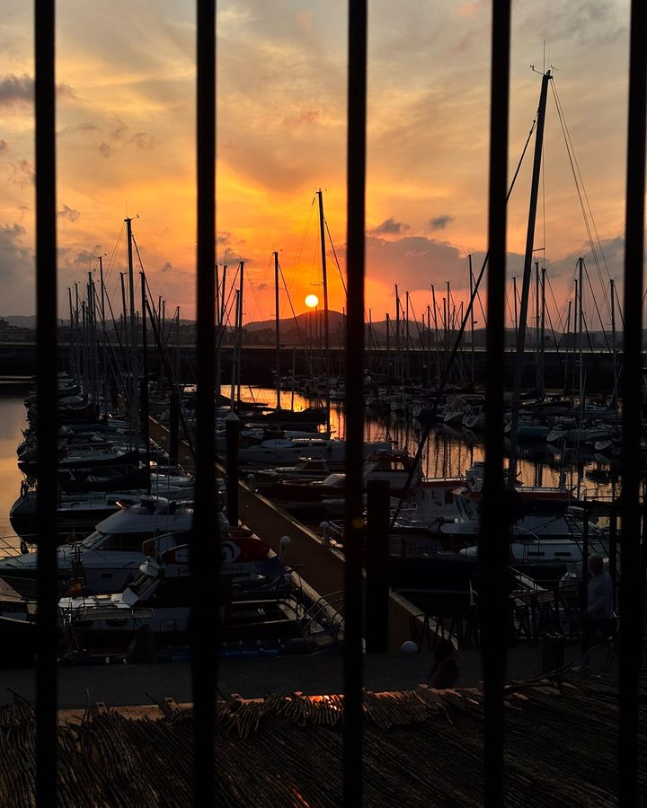 Puesta de sol naranja sobre un puerto deportivo lleno de barcos