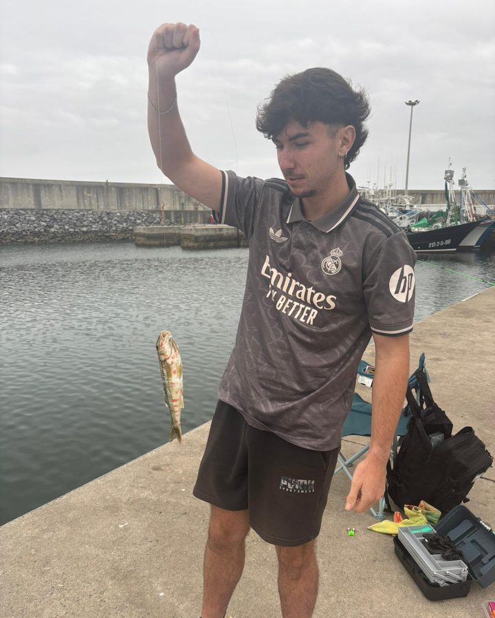Mario levantando el puño con un pez recién pescado en el puerto