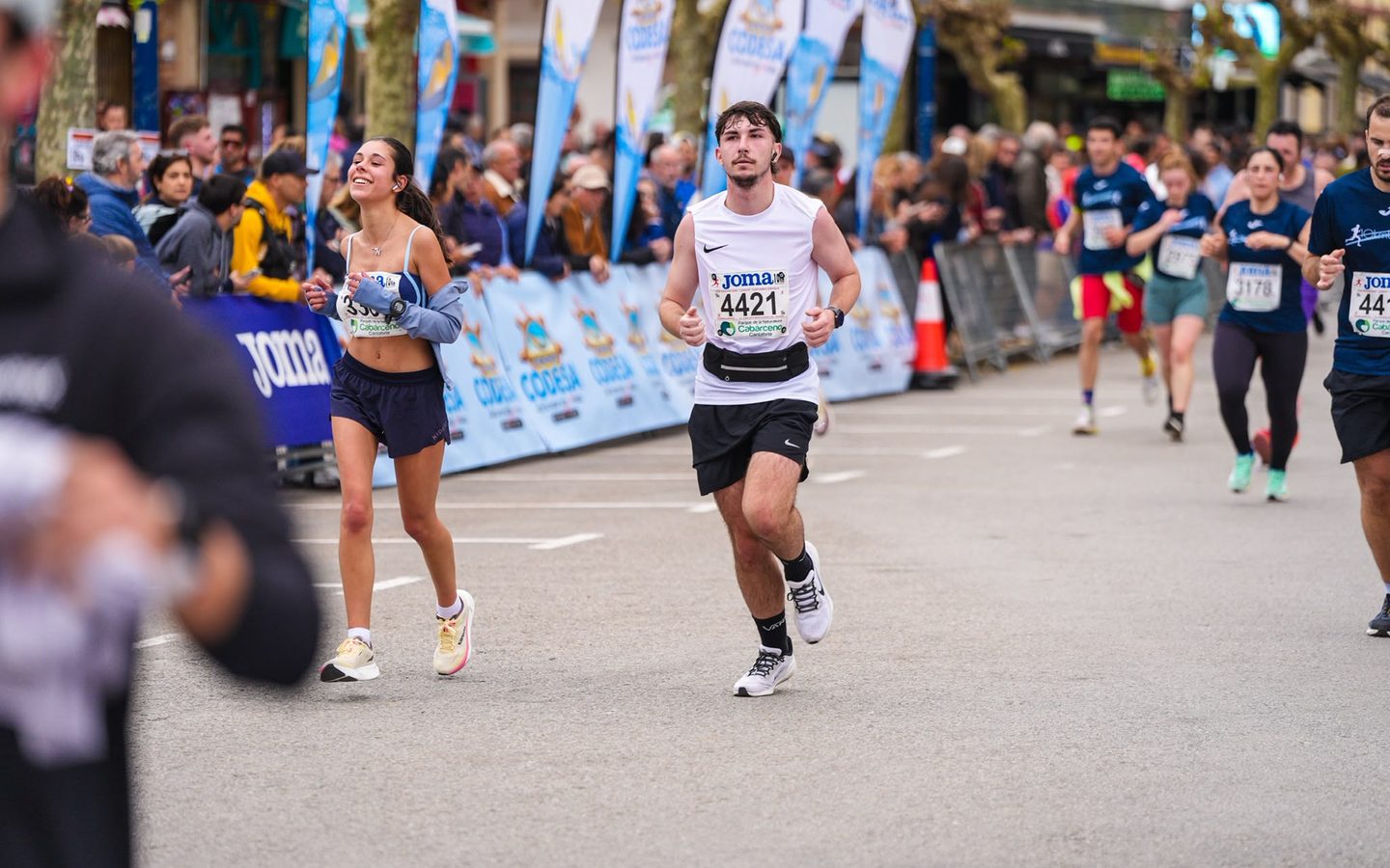 Mario corriendo por una calle con público a los lados durante una carrera