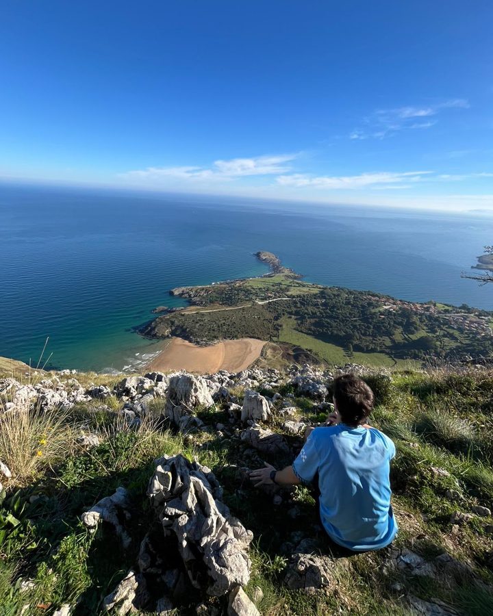 Mario sentado en una cima con vistas al mar