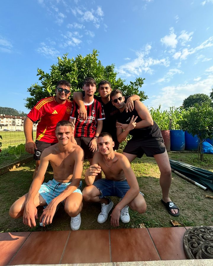 Cinco amigos posando en un jardín durante una barbacoa de verano