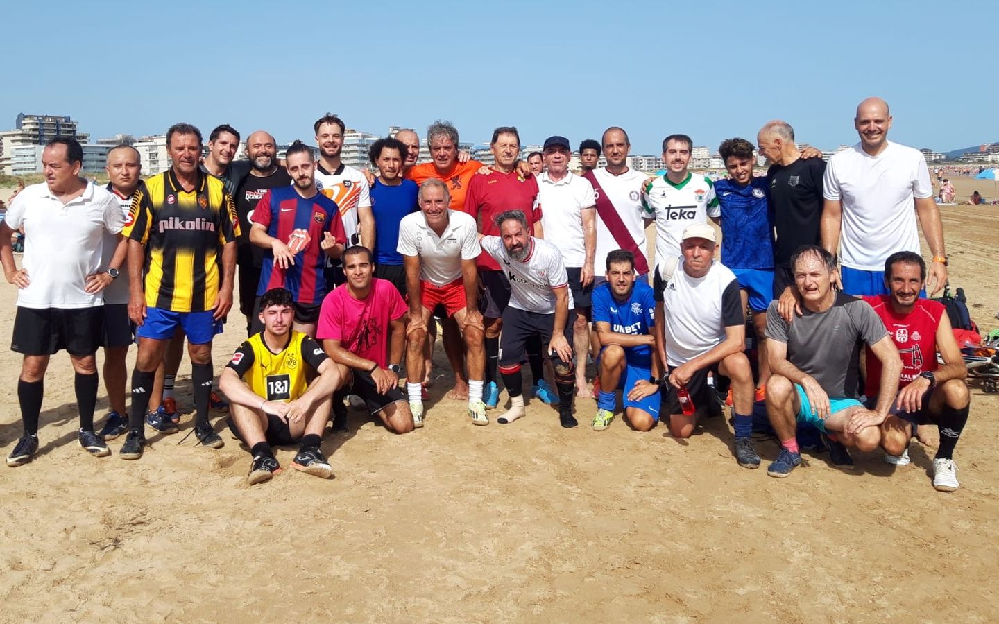 Grupo de amigos posando en la playa después de un partido de fútbol