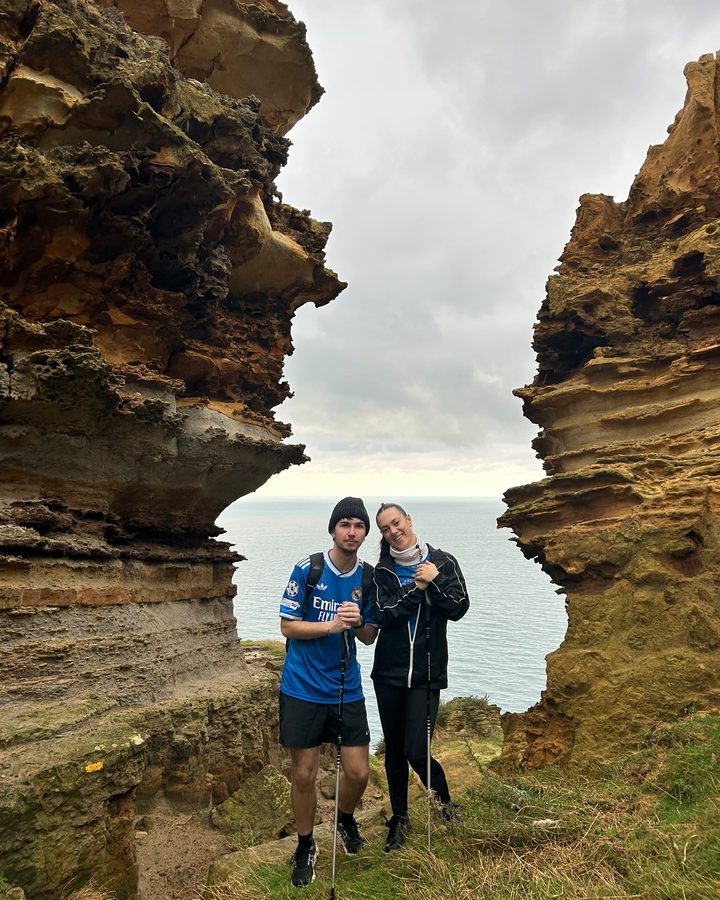 Mario y una amiga entre dos paredes de roca con el mar al fondo